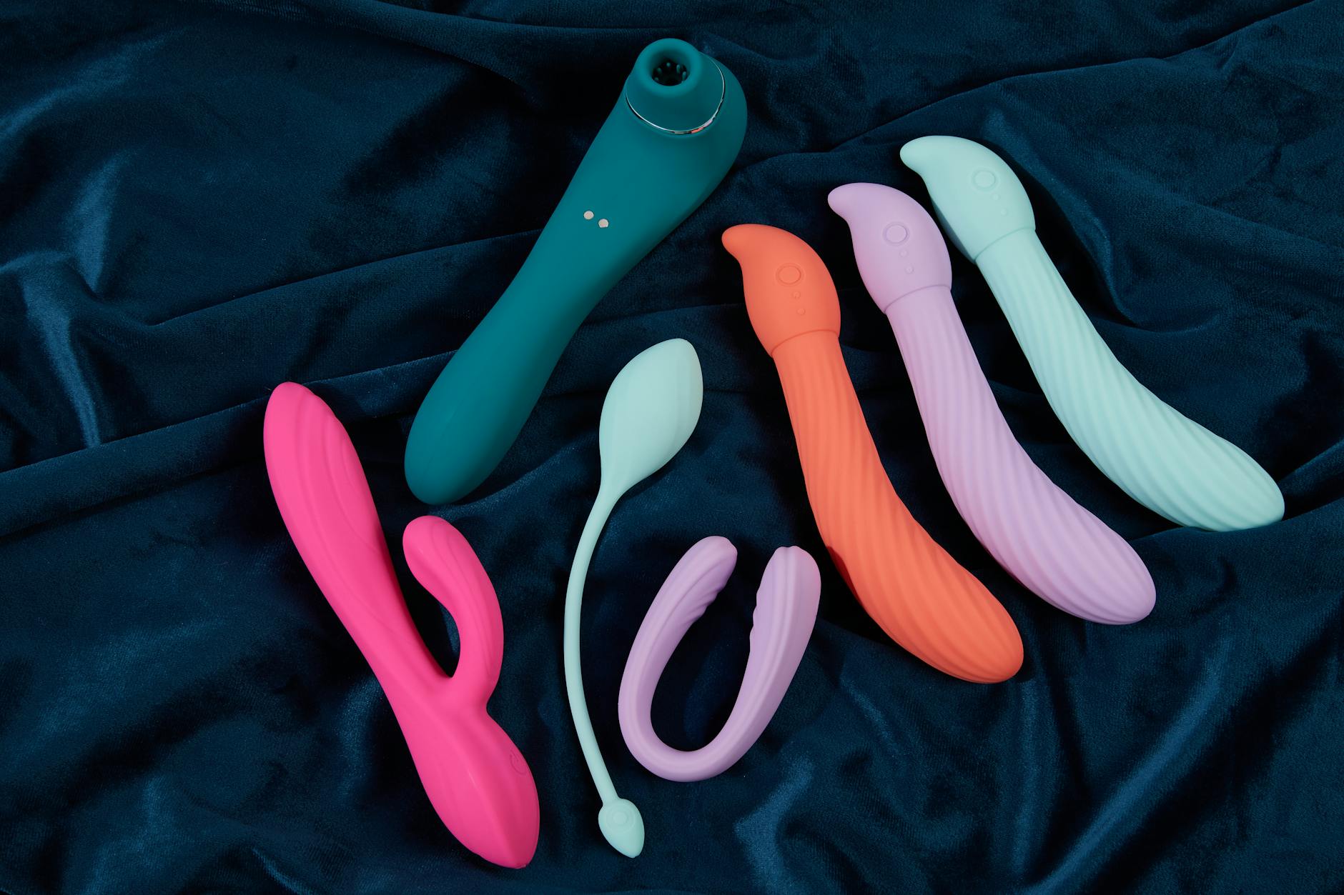 Vibrant collection of colorful clitoral vibrators arranged on a bright yellow surface