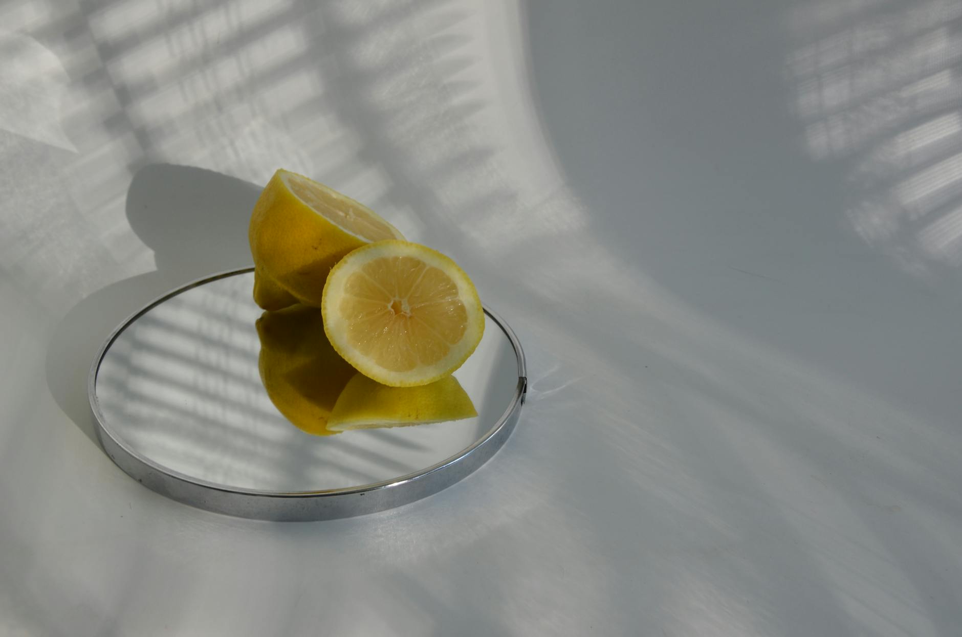 A teal lemon clitoral vibrator resting on white silk fabric