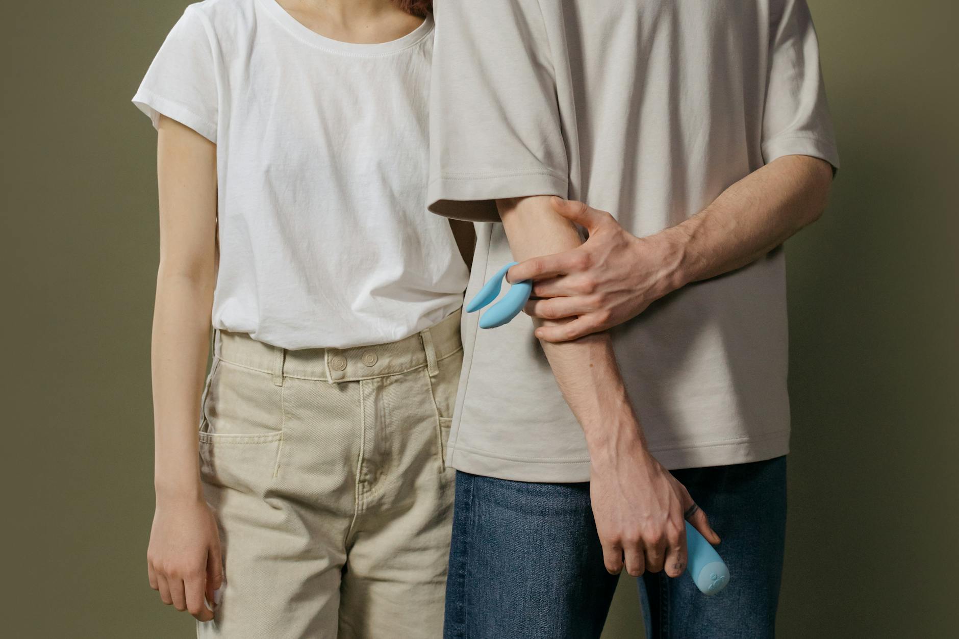 A young couple standing together indoors, exploring intimacy with a vibrator, symbolizing modern connection.